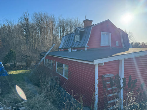 Tak med bandtäckning på hus i Valdemarsvik, nyligen ommålat för förbättrat skydd och estetiskt utseende.